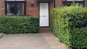 A two-story brick house with a white door, numbered 19, and a small garden area with hedges. - Centre of Town, 3 bedrooms, sleeps 6, own parking and patio close to The Oracle (Reading)