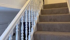 A staircase with white balusters and carpeted steps leading to a dark doorway. - Centre of Town, 3 bedrooms, sleeps 6, own parking and patio close to The Oracle (Reading)