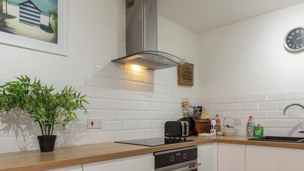 A modern kitchen with white cabinets, a stainless steel range hood, a toaster, and a sink. - Centre of Town, 3 bedrooms, sleeps 6, own parking and patio close to The Oracle (Reading)