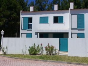 Un edificio de dos pisos con fachada blanca y contraventanas azules.