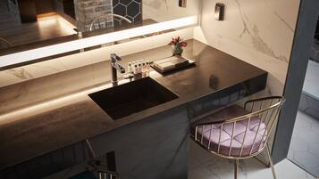 A modern kitchen with a marble backsplash, a built-in sink, and two bar stools.