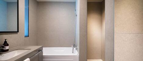 A modern bathroom with a bathtub, a large mirror, and a towel rack.