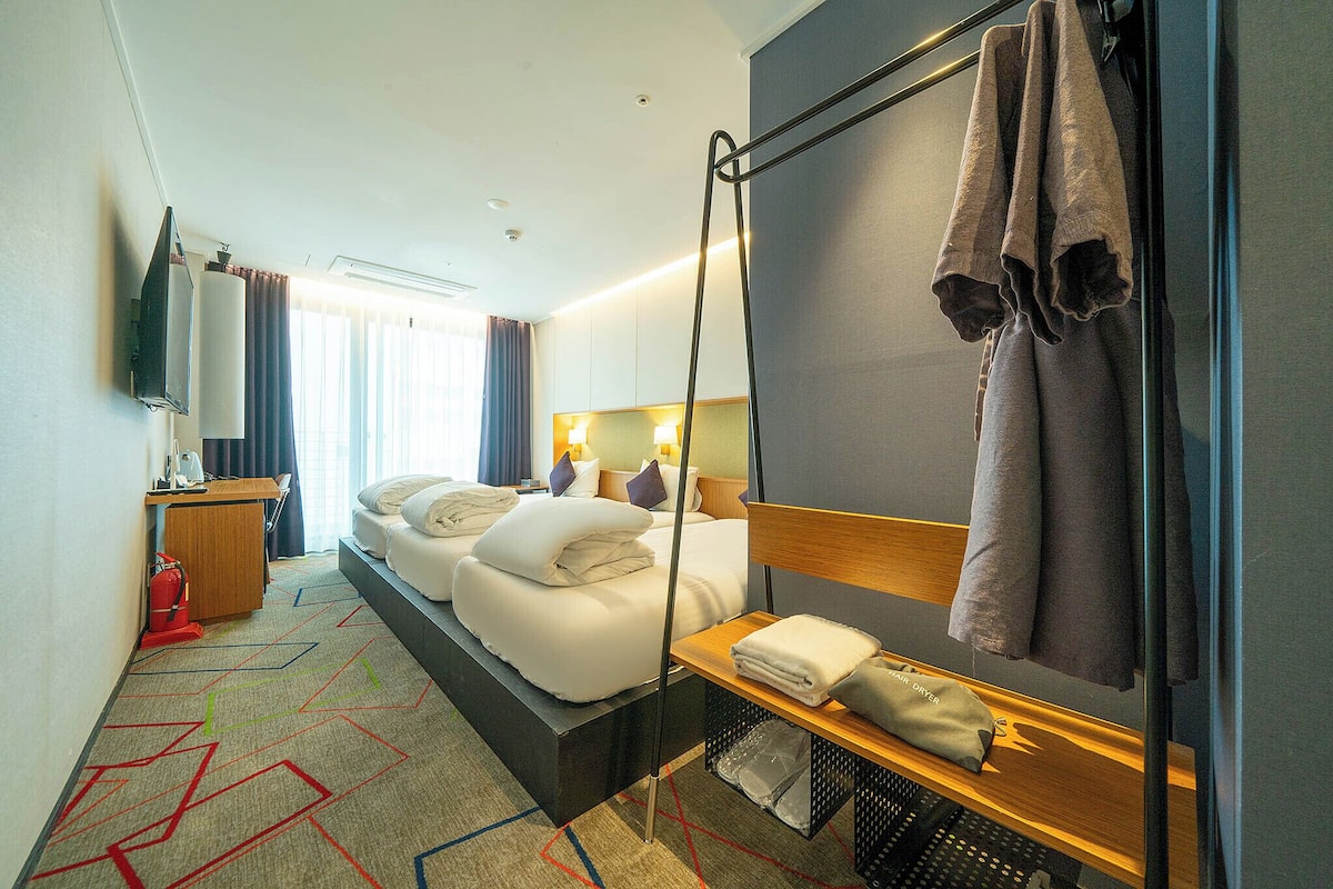 A hotel room with a bed, bedside table, and a large mirror.