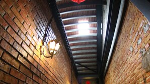 A narrow brick corridor with patterned tiles on the floor, a ceiling with exposed beams, and wall-mounted light fixtures. - Ban Loong Hotel (Ipoh)