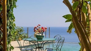 Una mesa con un jarrón de flores y vista al mar.