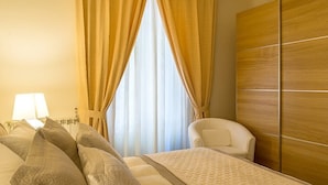 Habitación de hotel con cama, una silla, armario y ventana con cortinas.