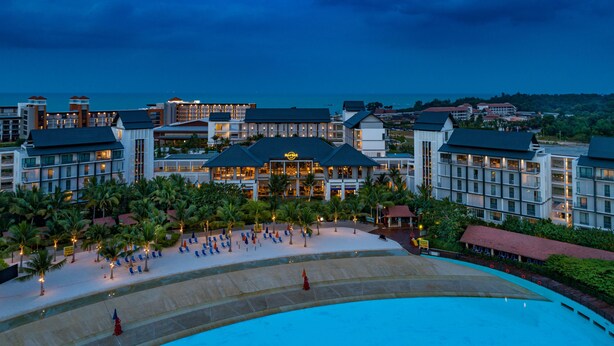 Een resort met een groot zwembad, meerdere gebouwen en een goed verlicht strand.