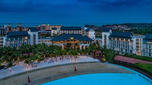 Un resort con una piscina grande, varias edificaciones y una zona de playa bien iluminada.