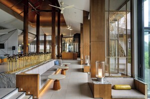 Un intérieur moderne avec de hauts plafonds, des poutres en bois et un espace salon agrémenté de tables et de canapés.