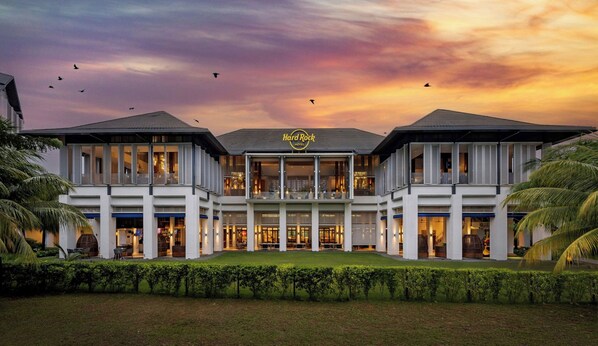 A hotel with a central atrium, multiple floors, and a landscaped front garden.