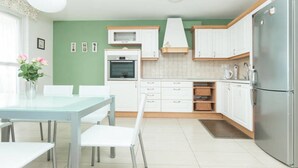 Una cocina moderna con armarios blancos, horno empotrado y refrigerador.