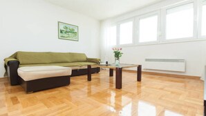 Una sala de estar con un sofá verde, una mesita y una ventana con marcos blancos.
