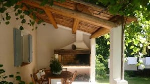Une terrasse extérieure dotée d’une pergola en bois, d’une table à manger avec des chaises et d’un barbecue.