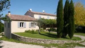 Une maison à deux étages avec un mur en pierre et une allée gravillonnée.