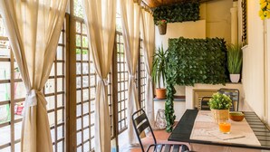 Un comedor con una mesa, sillas, una planta colgante y una planta en maceta en la pared.