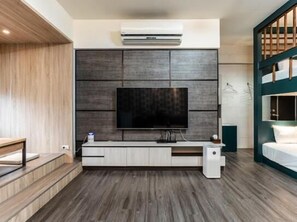 Un salon moderne doté d’un grand téléviseur à écran plat fixé au mur, ainsi que d’un système de climatisation intégré.