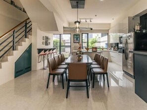 Una cucina moderna con un'isola grande, elettrodomestici in acciaio inossidabile e un'area pranzo con sedie.