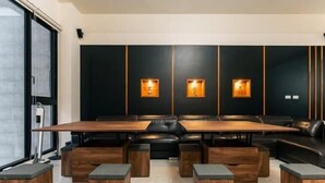 A modern conference room with a long table and black leather seating, illuminated by wall-mounted lights. - Jophina B&B (Donggang)