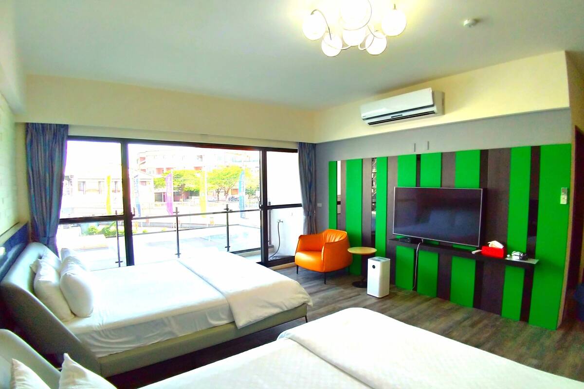 A hotel room with two beds, a television, and a view of the street.