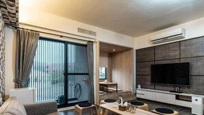 A modern living room with a sofa, a dining table, and a TV mounted on the wall. - Jophina B&B (Donggang)