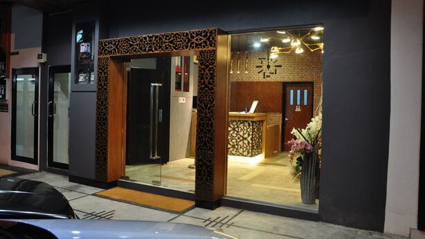 A modern hotel entrance with a reception desk, a glass door, and a decorative wall. - Valya Hotel - Kuala Terengganu (Kuala Terengganu)
