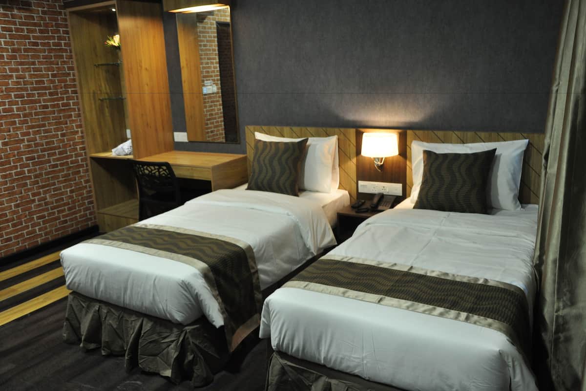 Une chambre d’hôtel avec deux lits, un bureau, une chaise, un miroir et un mur avec un motif en briques.