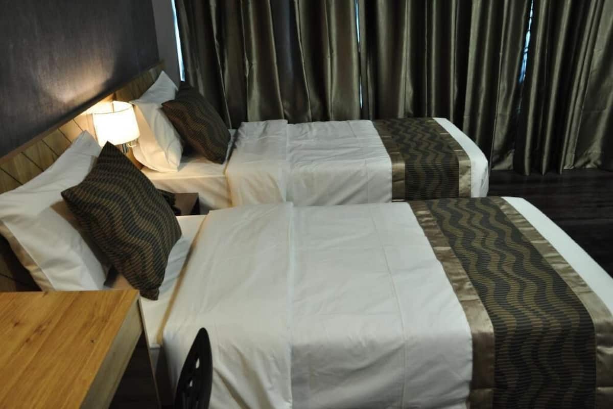 Une chambre d’hôtel avec deux lits, une table de chevet, une lampe et une vue sur des rideaux.