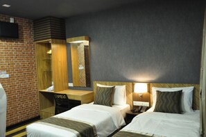 A hotel room with two beds, a desk, a mirror, and a TV on the wall. - Valya Hotel - Kuala Terengganu (Kuala Terengganu)
