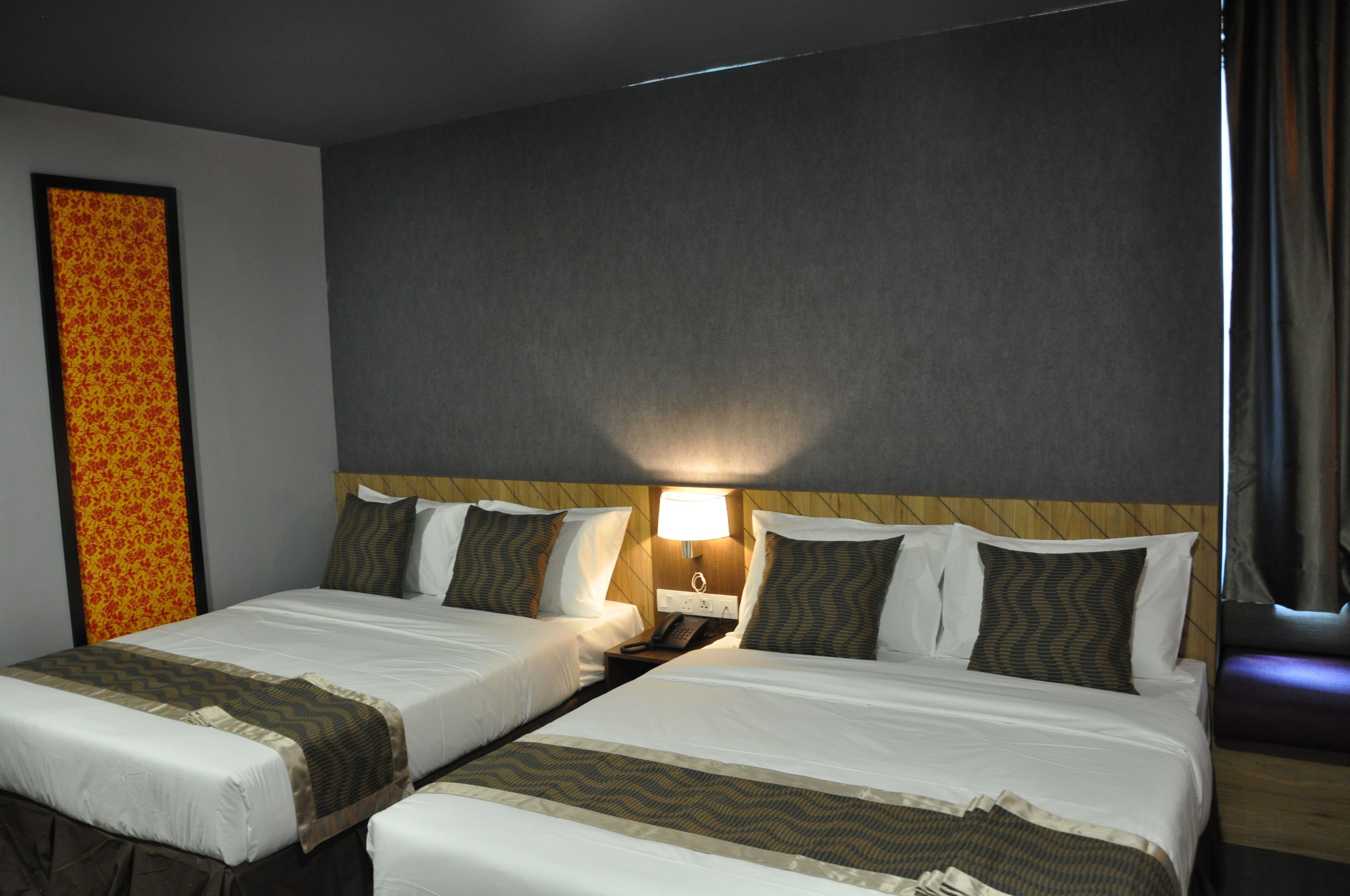 A hotel room with two beds, a nightstand with a lamp, and a patterned wall decoration.