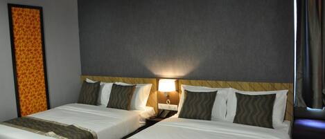 A hotel room with two beds, a nightstand with a lamp, and a patterned wall decoration.