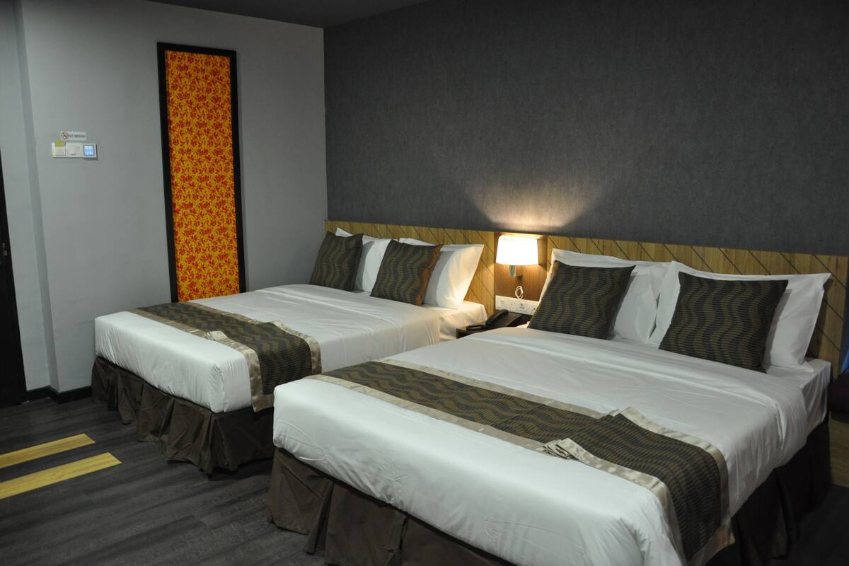 Une chambre d’hôtel avec deux lits, chacun doté d’une tête de lit, de tables de chevet et de lampes.