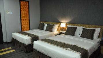 Ein Hotelzimmer mit zwei Betten, jeweils mit Kopfteil, Nachttischen und Lampen.