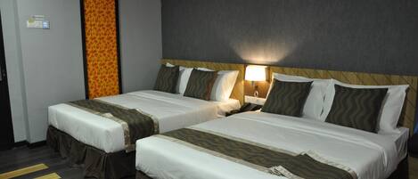 A hotel room with two beds, each with a headboard, bedside tables, and lamps.