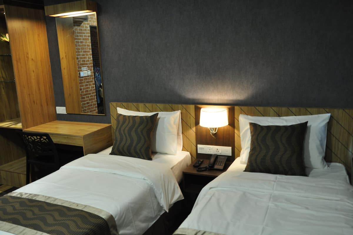Une chambre d’hôtel avec deux lits, un bureau et un miroir.