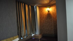 A room with a brick wall, a window with curtains, and a bed with a pillow. - Valya Hotel - Kuala Terengganu (Kuala Terengganu)