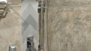 A shower with a handheld showerhead and a wall-mounted rainhead in a bathroom with a tiled wall and a towel rack. - Valya Hotel - Kuala Terengganu (Kuala Terengganu)