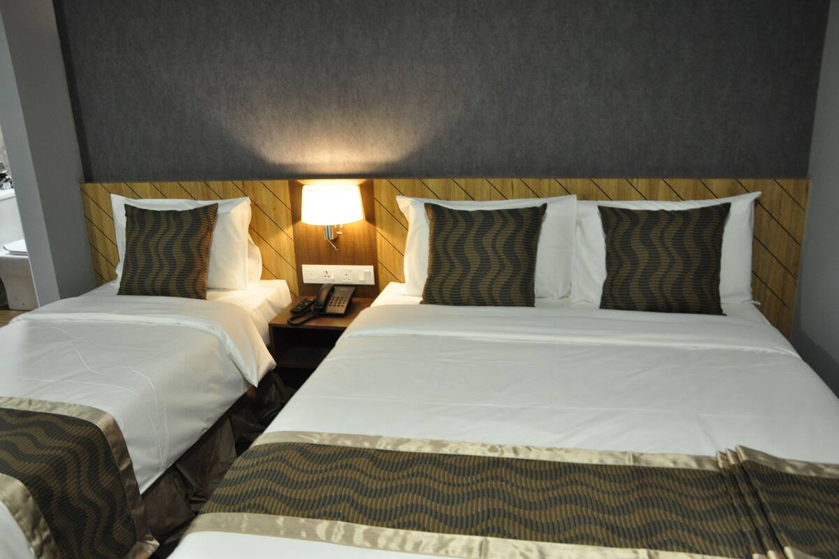 Une chambre d’hôtel avec deux lits, une tête de lit en bois, une table de chevet avec une lampe et un téléphone.