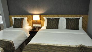 A hotel room with two beds, a wooden headboard, a nightstand with a lamp, and a telephone.