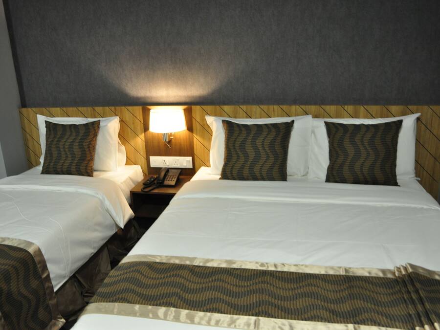 A hotel room with two beds, a wooden headboard, a nightstand with a lamp, and a telephone.