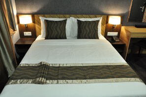 A neatly made bed with a patterned bedspread, two bedside lamps, and a wooden headboard. - Valya Hotel - Kuala Terengganu (Kuala Terengganu)