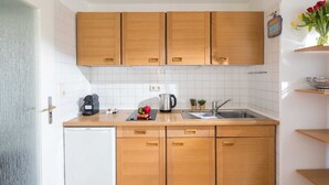 Une cuisine de taille réduite, avec des meubles de rangement en bois, un réfrigérateur blanc et un évier.