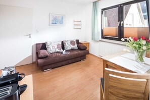 Un salon chaleureux avec un canapé marron, une table en bois et une fenêtre équipée de stores.