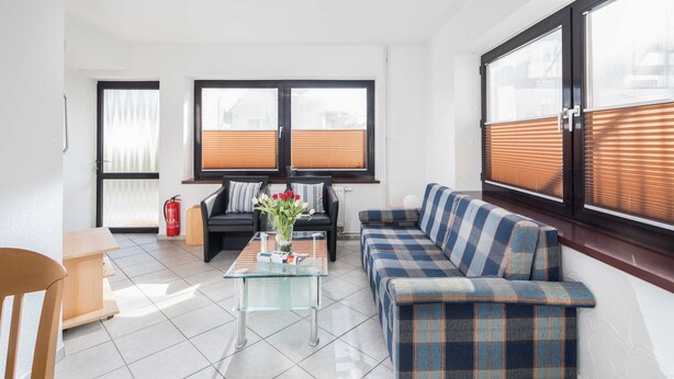 Un salon moderne avec un canapé, une table basse en verre et une petite table sur laquelle est posé un vase de fleurs.
