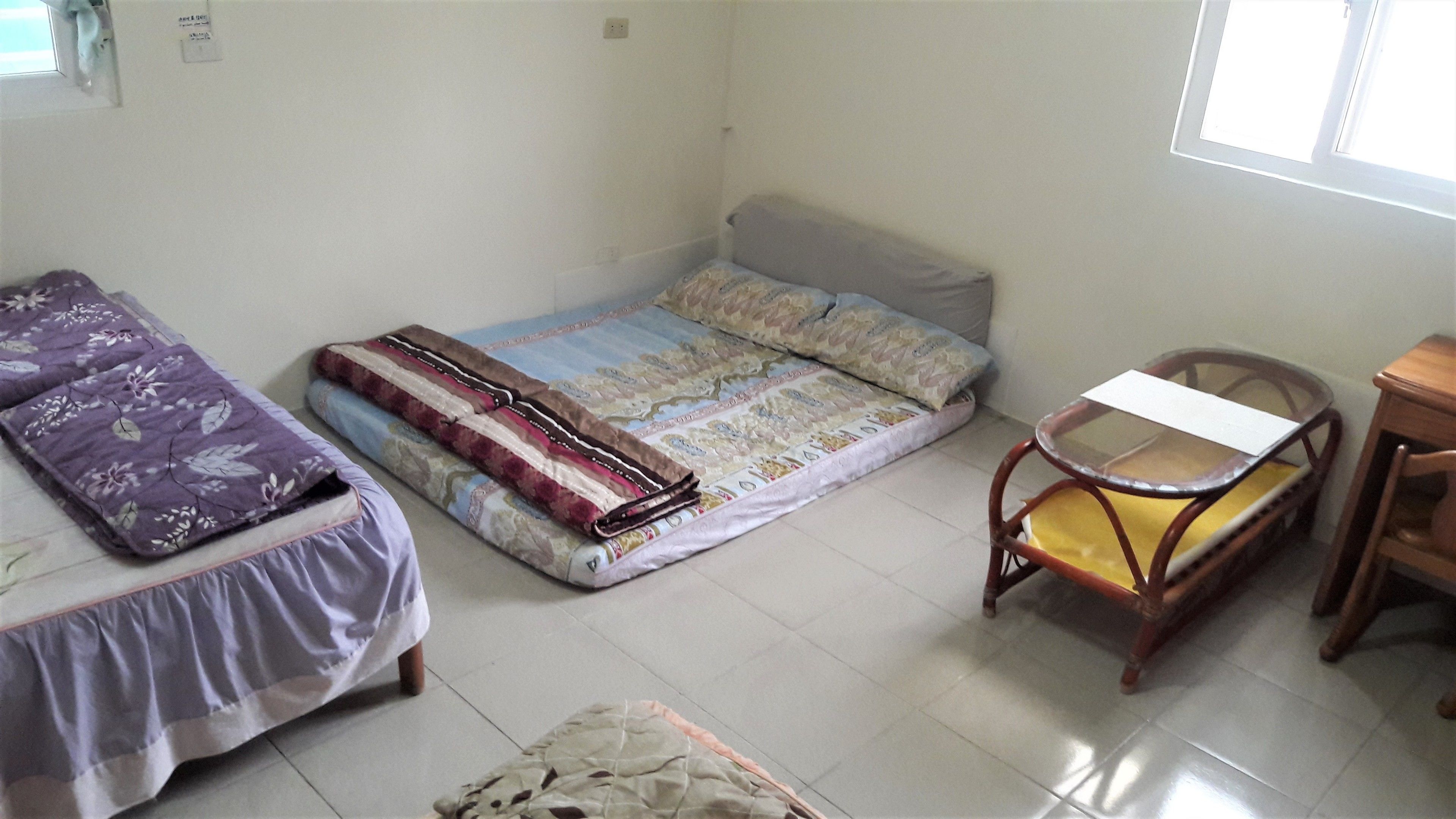 A small, clean room with a bed, a chair, and a table.