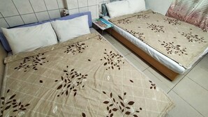 A double bed with floral-patterned bedding, a bedside table with a magazine, and a window with blue curtains. - Hai Xia Your Home (New Taipei City)