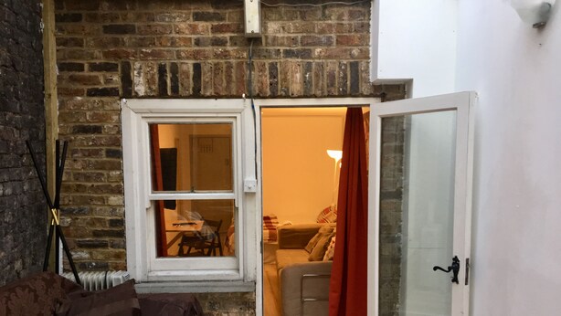 A room with a brick wall, a white door, and a window. - Stay in Kings Cross - Flat D (London)