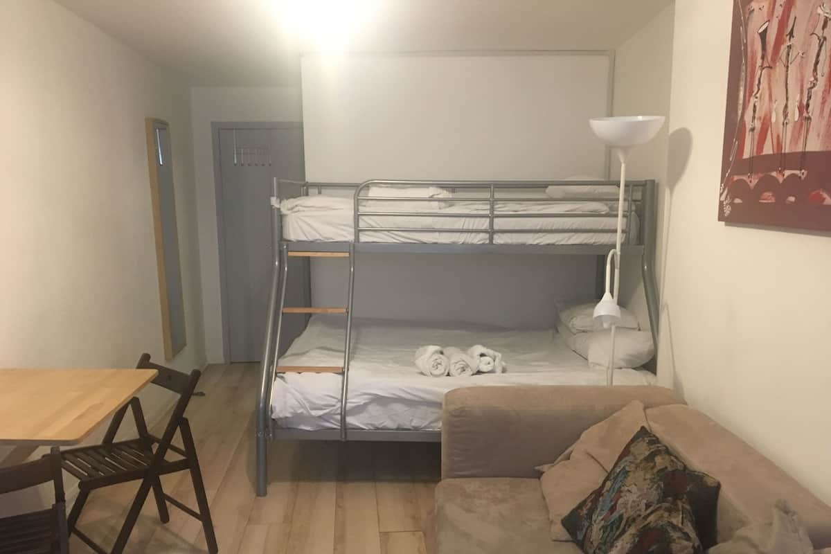 A bunk bed with a desk and chair, a couch, and a lamp.