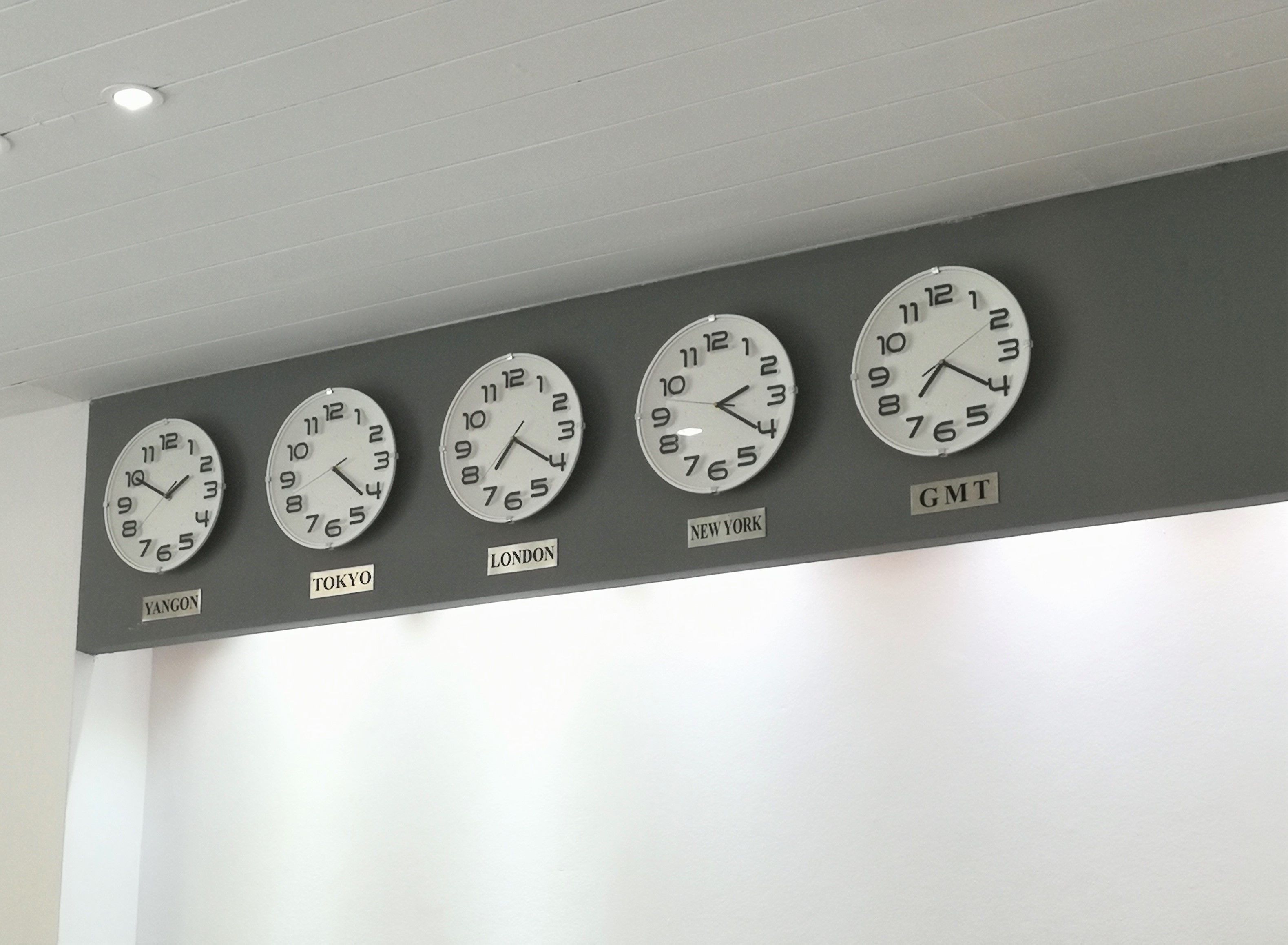 A row of wall clocks displaying times from different cities.