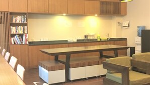 A modern kitchen with wooden cabinets, a long dining table, and two pendant lights. - Yama Hotel & Rooftop Bar (Yangon)