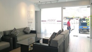 A modern reception area with a sofa, coffee table, and wall art. A man is seen outside the entrance. - Yama Hotel & Rooftop Bar (Yangon)